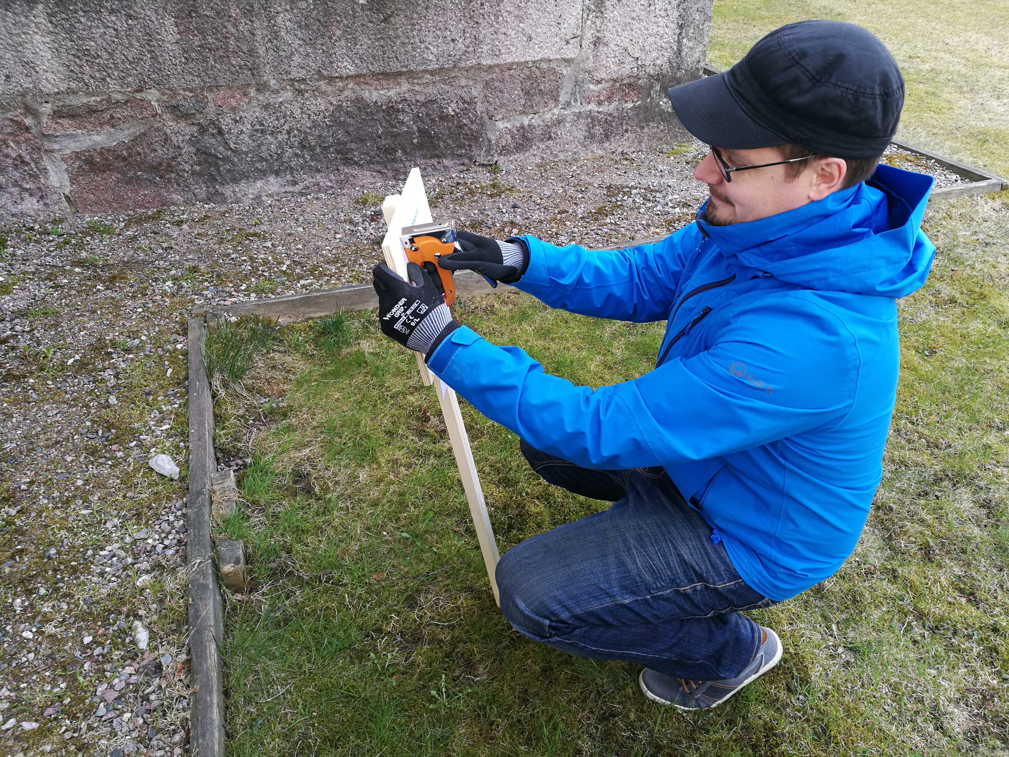 Tuomas Niskanen pystyttää rastitaulua kirkon vierellä