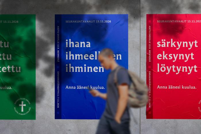 ihminen kävelee seurakuntavaalijulisteiden ohi